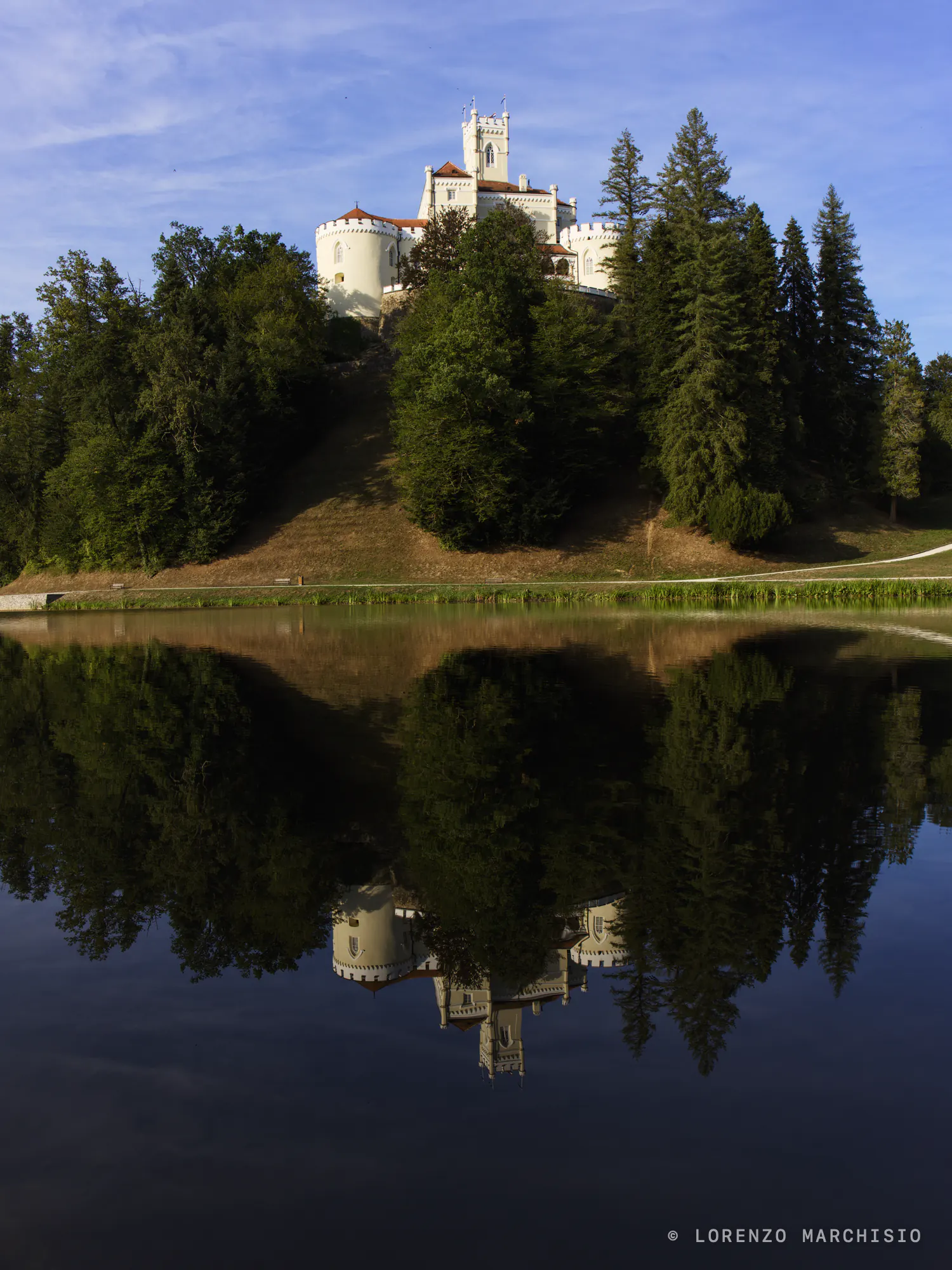 Trakošćan Castle on its wooded hill, mirrored in the still lake below